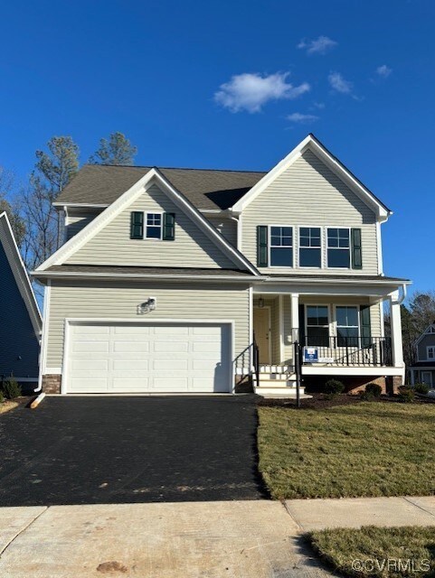View of front of property with a front yard, a gar