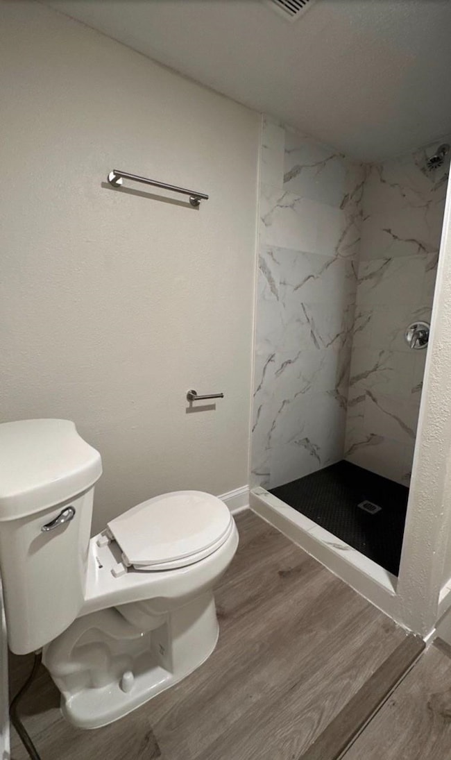 Full bathroom with a marble finish shower and wood finished floors