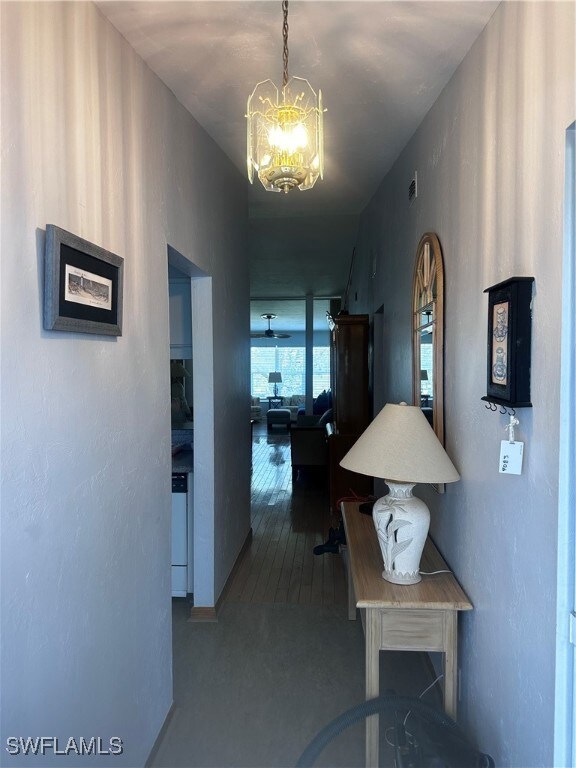Hallway featuring a chandelier and a textured wall