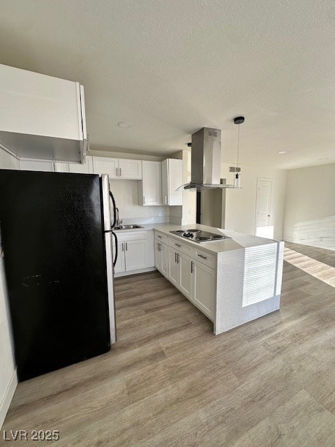 Kitchen featuring fridge, white cabinets, light wood finished floors, hanging light fixtures, and ventilation hood