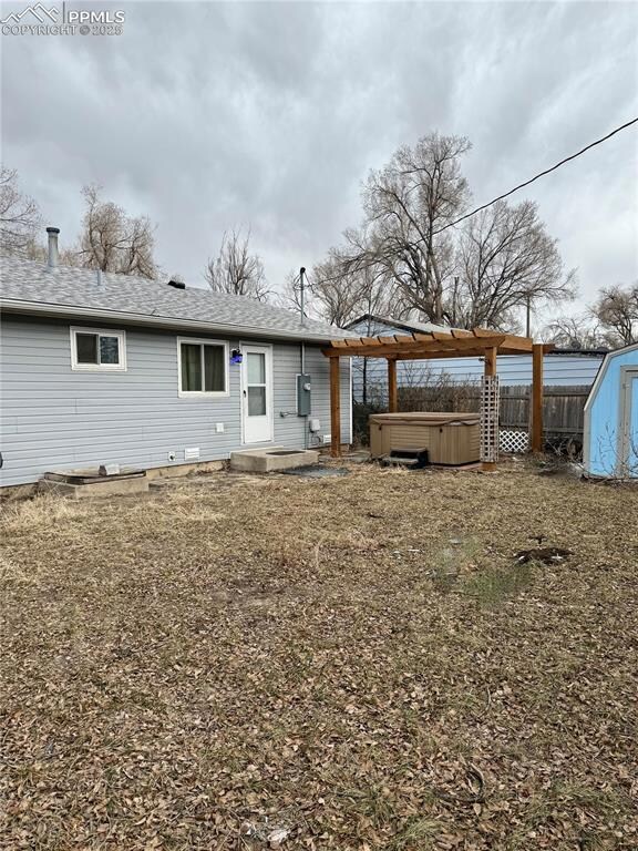 Back of house featuring a hot tub