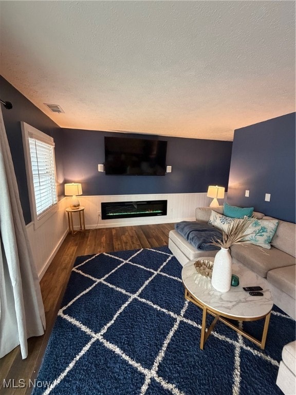 Living area with wainscoting, wood finished floors, a textured ceiling, and wood walls