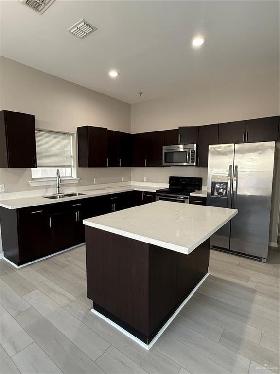 Kitchen with stove, light wood-type flooring, refrigerator, sink and a kitchen island.  all the modern conveniences and ready to Move in!