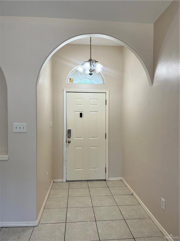 Foyer entrance with light tile flooring and a chandelier