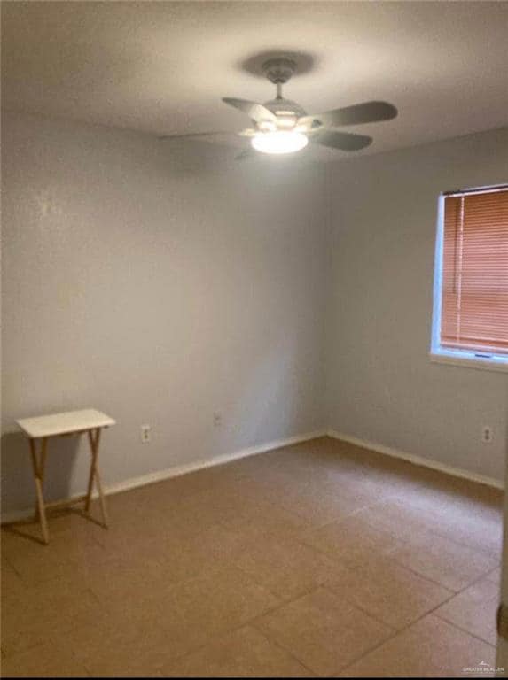 Empty room with ceiling fan and baseboards