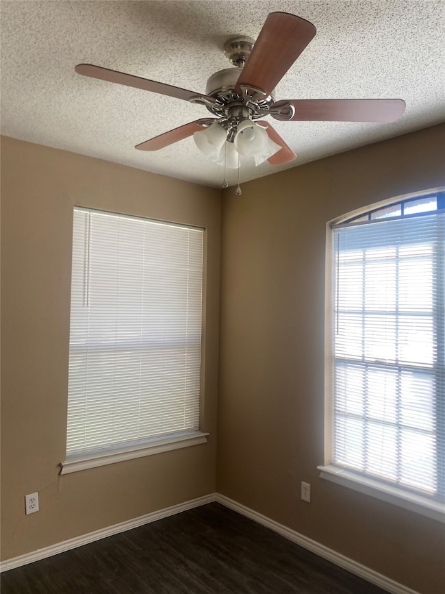 Spare room with a textured ceiling, dark wood-style floors, and a ceiling fan