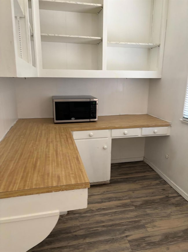 Unfurnished office featuring baseboards, dark woo