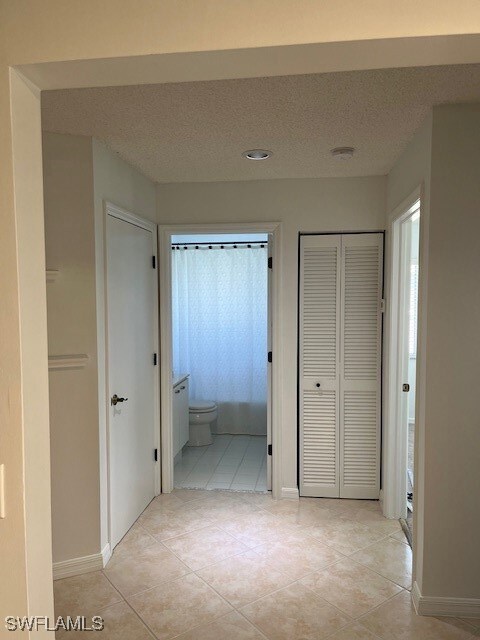 Hall featuring a textured ceiling and light tile p