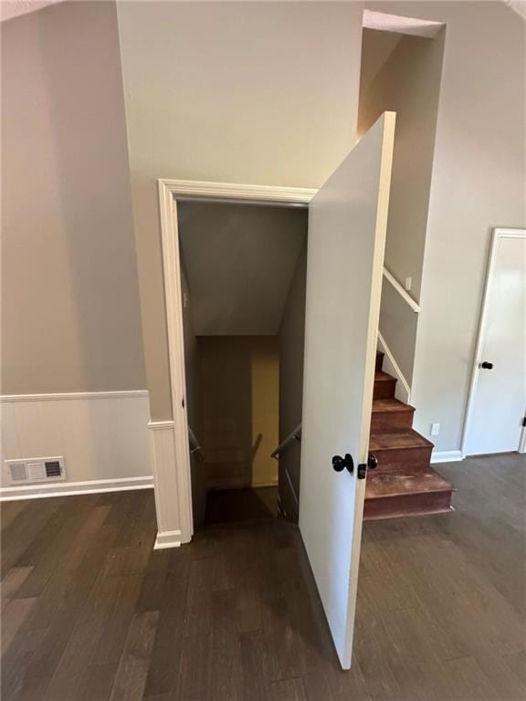 Stairs featuring wood finished floors and a wainscoted wall
