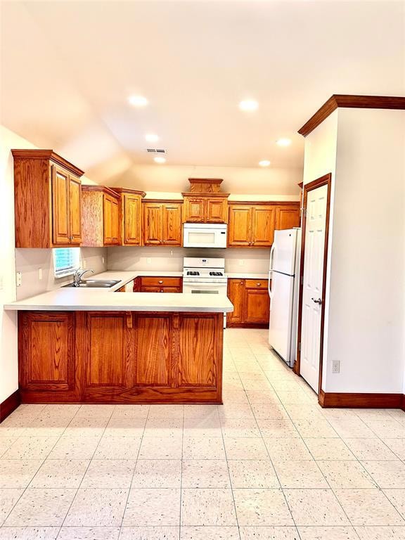 Kitchen with brown cabinetry, light countertops, recessed lighting, white appliances, and a peninsula