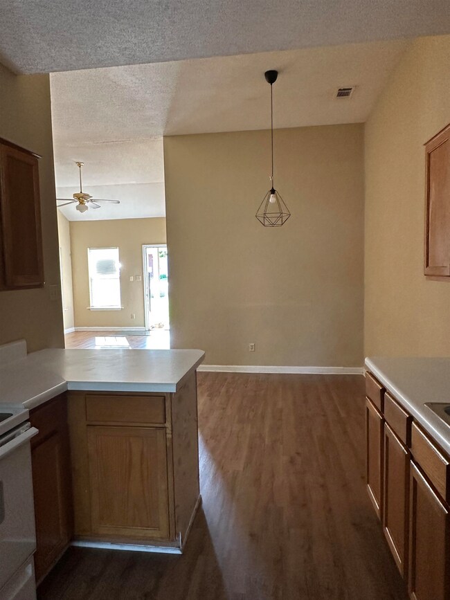 Kitchen with dark wood-style floors, a peninsula, light countertops, ceiling fan, and white range