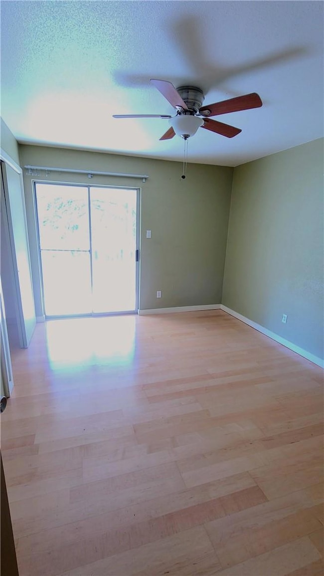 Empty room featuring ceiling fan and light wood-t