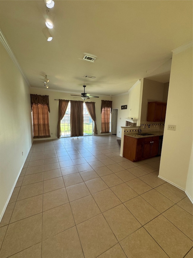 Unfurnished living room featuring light tile patterned flooring, a ceiling fan, and ornamental molding