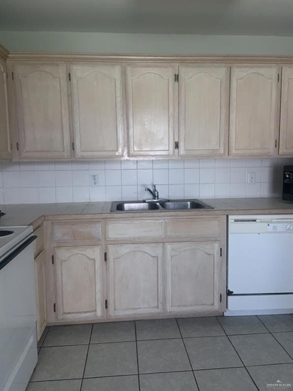 Kitchen with white appliances, a sink, tasteful backsplash, and light brown cabinetry