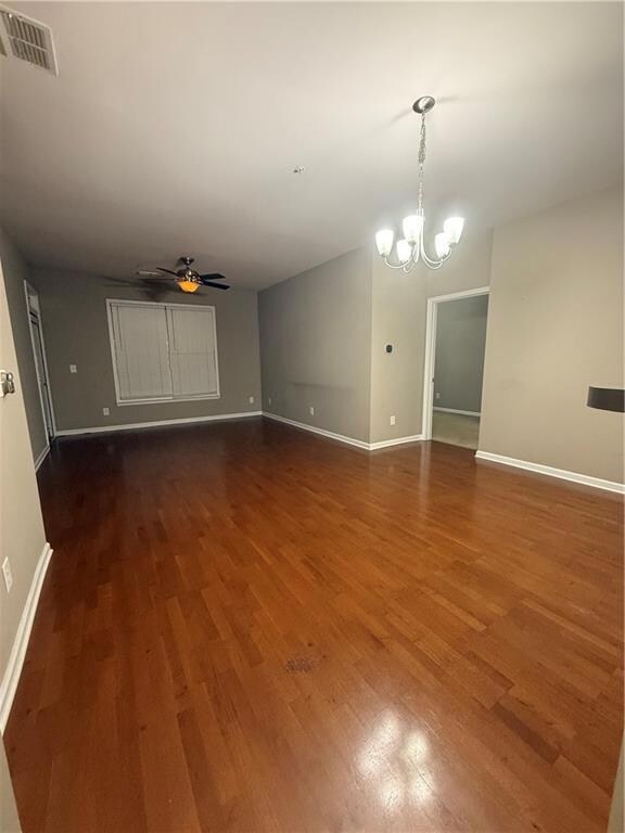Spare room with wood finished floors, a chandelier, and a ceiling fan