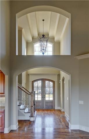 Looking from the great room back to the front door is one of many delightful features you will find- a beautiful chandelier in an airy foyer.