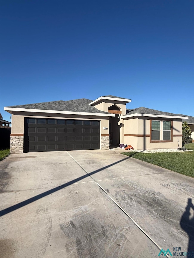 View of front of home featuring stone siding, stucco siding, a shingled roof, and driveway