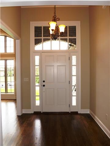 The two story foyer has a beautiful custom door with overhead transom window. 