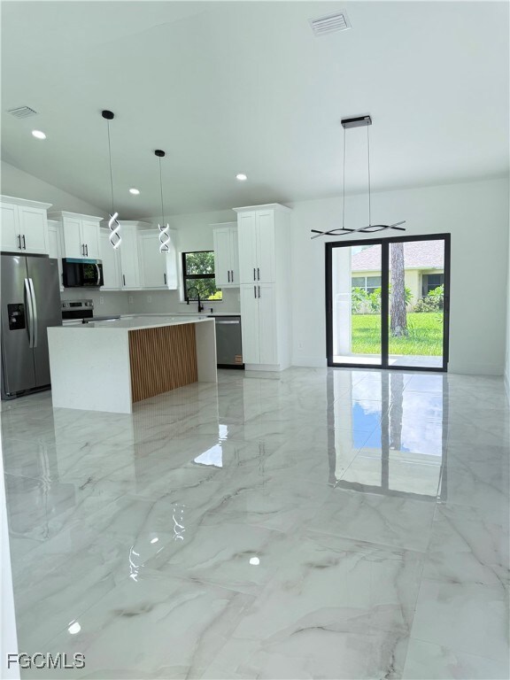 Kitchen with decorative light fixtures, light marble finish floors, stainless steel appliances, white cabinets, and recessed lighting