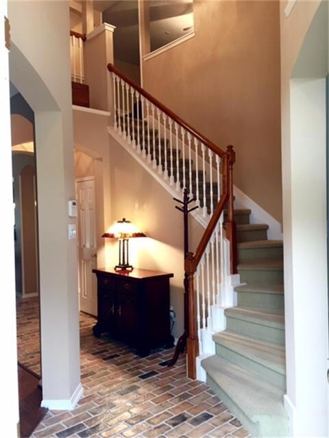Inviting foyer featuring brick flooring, high ceilings and warm, neutral colors.