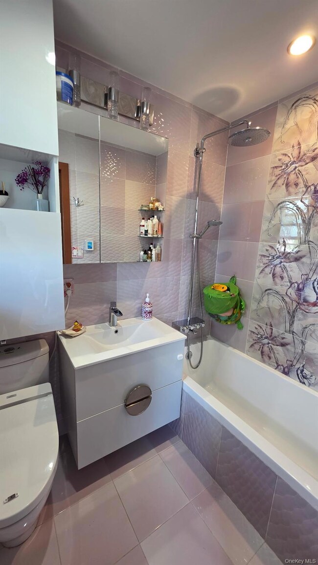 Bathroom with tiled shower / bath combo, vanity, tile walls, and light tile patterned floors