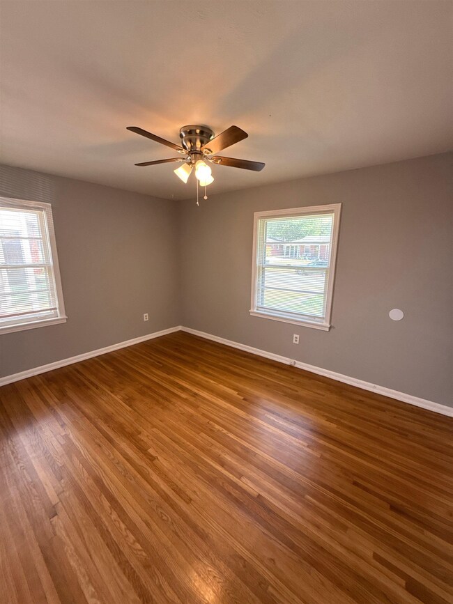 Empty room featuring healthy amount of natural light, wood finished floors, and a ceiling fan