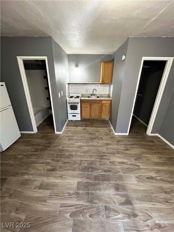 Kitchen featuring white appliances, a sink, basebo