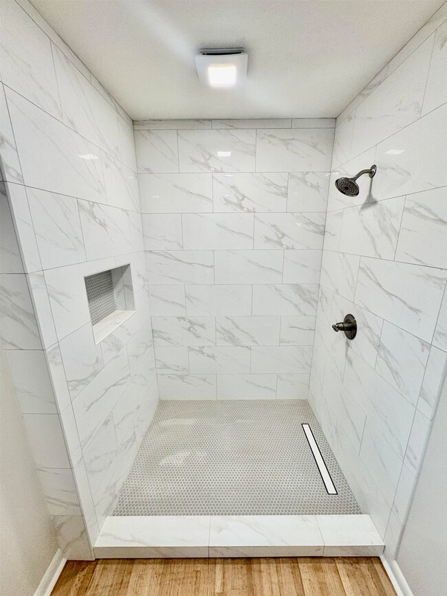 Full bath with a tile shower and wood finished floors