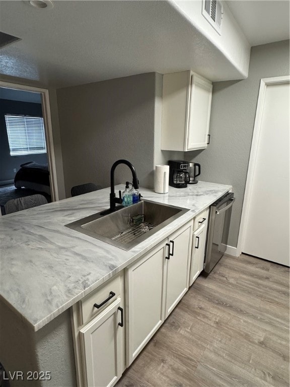 Kitchen featuring white cabinets, light stone coun