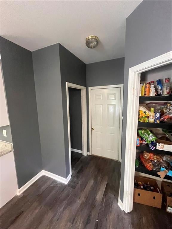 Hall featuring dark wood-style flooring and baseboards