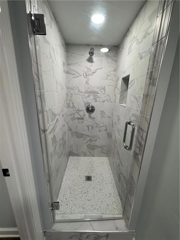 Full bath with a shower stall and marble finish floors