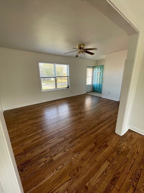 Empty room with dark wood-style floors and ceiling fan