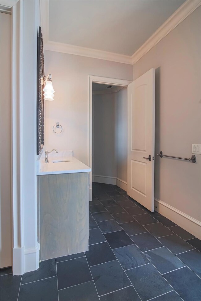 Bathroom with vanity, baseboards, and crown moldin