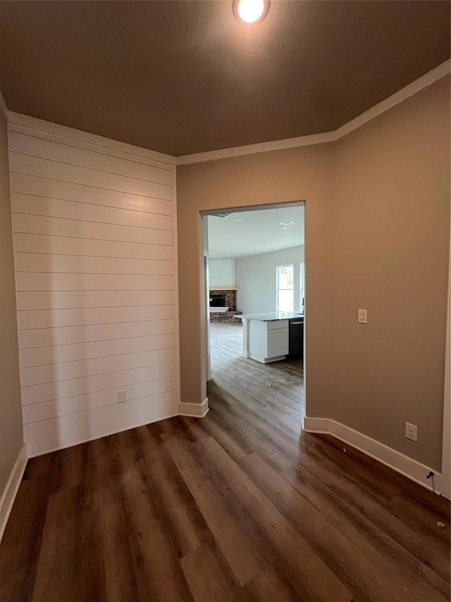 Empty room featuring baseboards and dark wood-styl