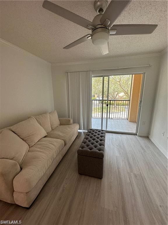 Living area featuring light wood-style floors, crown molding, a textured ceiling, and a ceiling fan