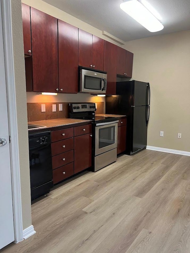 Kitchen with black appliances, baseboards, dark b