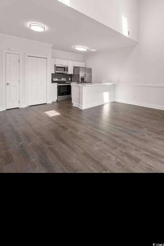 Unfurnished living room featuring dark wood finished floors and baseboards