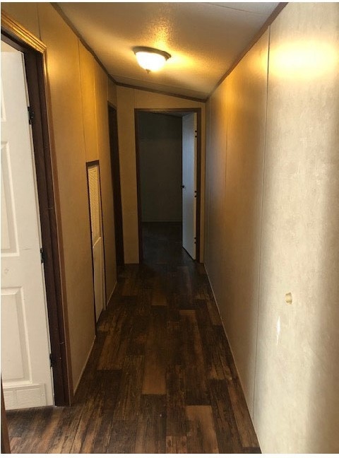 Hallway featuring dark wood finished floors and vaulted ceiling