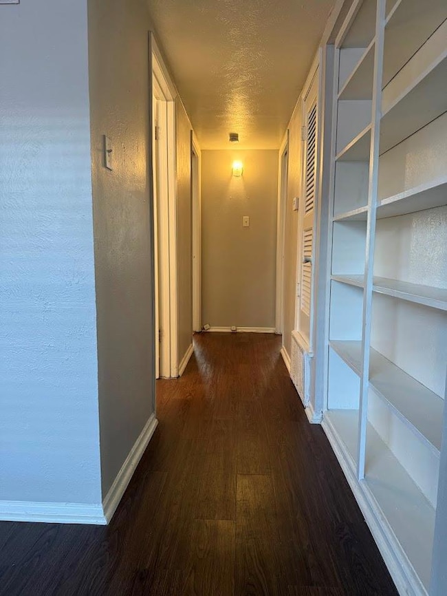Corridor with wood finished floors, baseboards, a