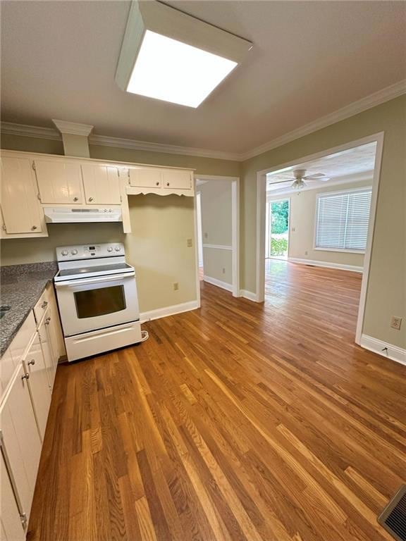 Kitchen with electric range, under cabinet range hood, wood finished floors, crown molding, and baseboards