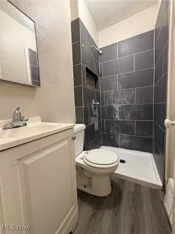 Bathroom featuring wood finished floors, a stall shower, vanity, and a textured ceiling