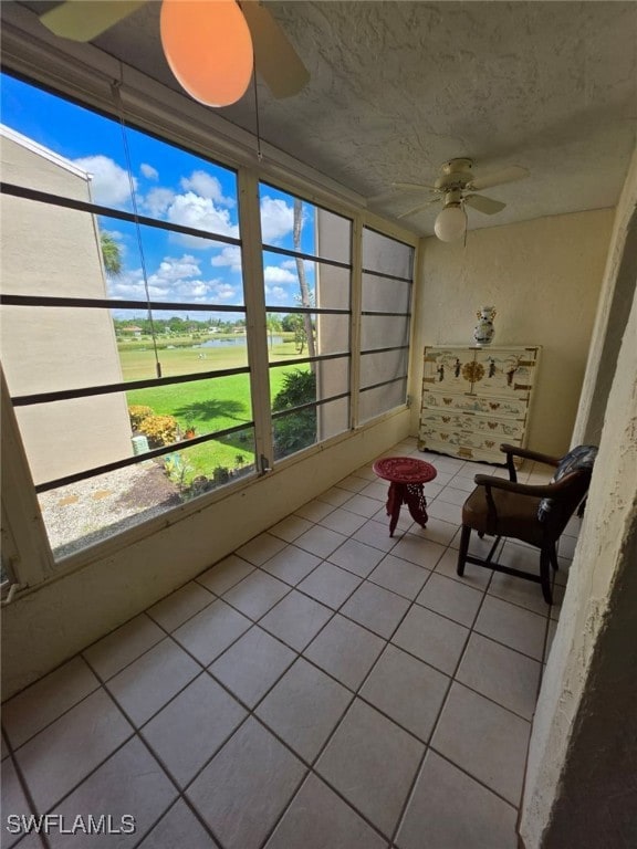 Sunroom featuring tile patterned flooring, a water view, and a textured ceiling