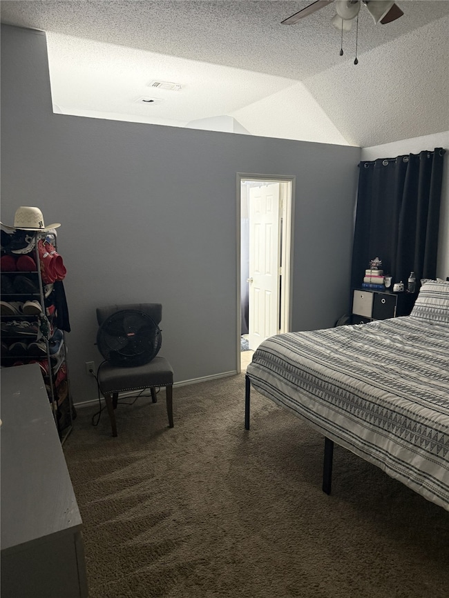 Bedroom with a textured ceiling, carpet floors, lofted ceiling, and ceiling fan