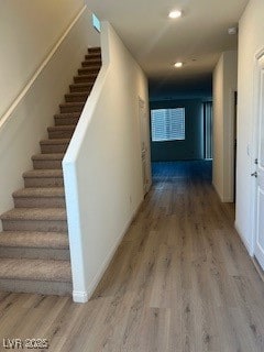 Hallway with light wood-type flooring, stairway, and recessed lighting