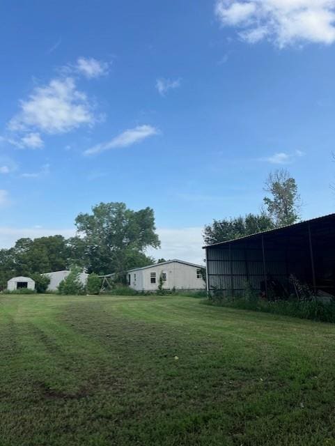 View of grassy yard featuring a pole building and an outdoor structure