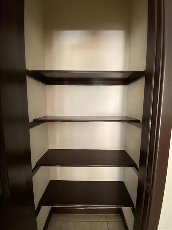 Tiled spare room featuring a notable chandelier