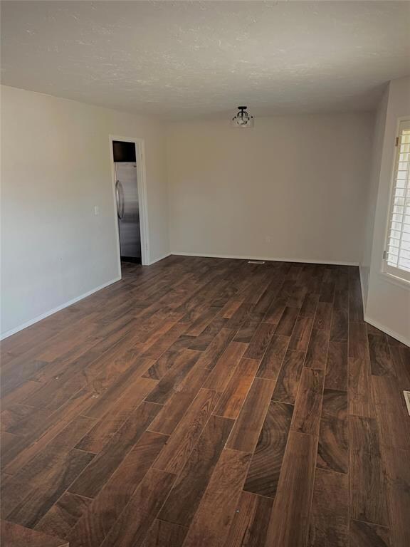 Unfurnished room with dark wood-type flooring