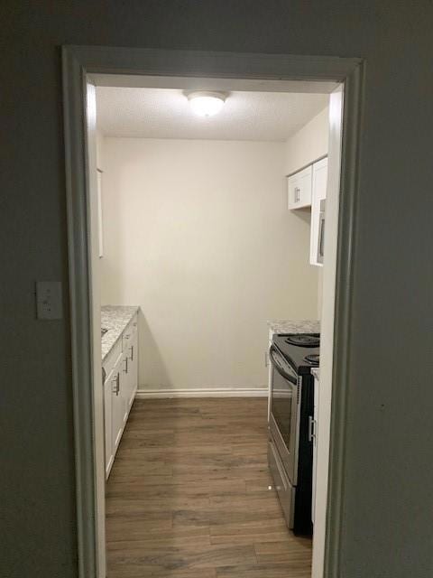 Kitchen with a textured ceiling, stove, white cabi