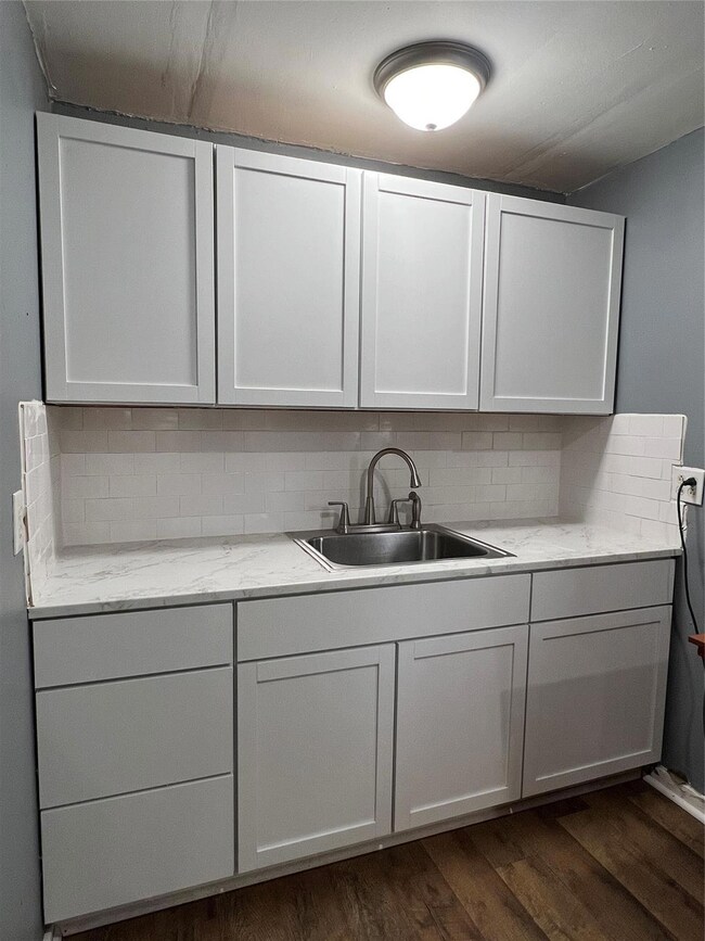 Kitchen with tasteful backsplash, light stone coun
