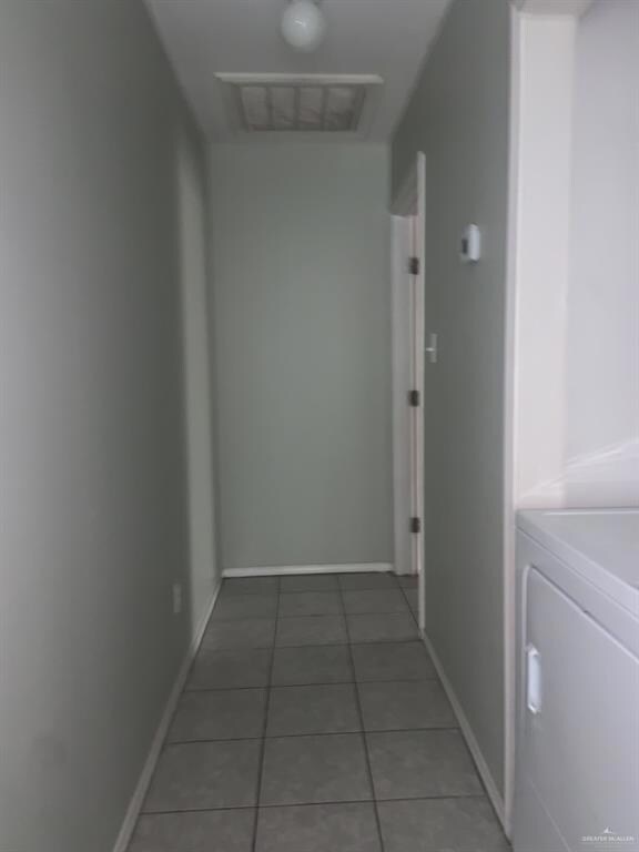 Hall with light tile patterned floors, washer / clothes dryer, and baseboards